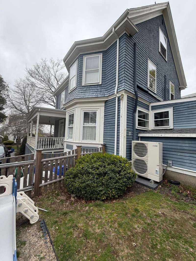 A blue-gray Victorian house with white trim and a bay window, exterior finished.