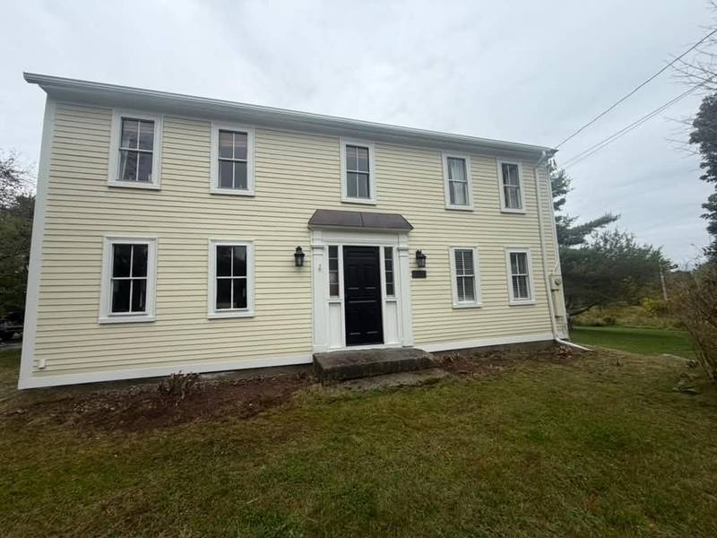 The same colonial repainted cream with white trim and a black door.