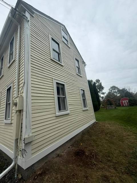 Gable end of a cream colonial after painting, with white corner boards.