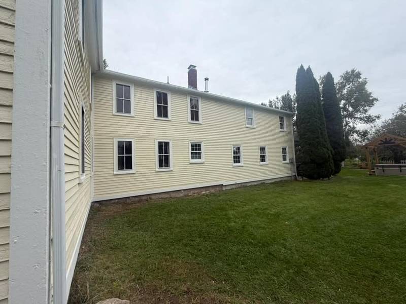 Long side of a freshly painted cream colonial with white window trim.