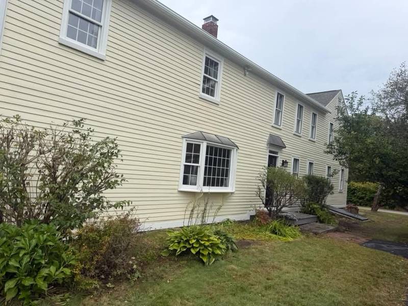 Side of a cream colonial with a white bay window and fresh trim.