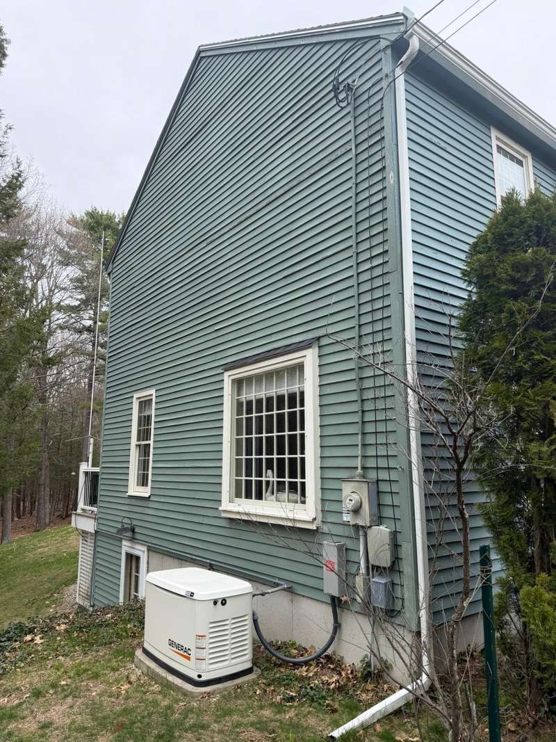 The gable end of a house in teal green siding with white window trim.