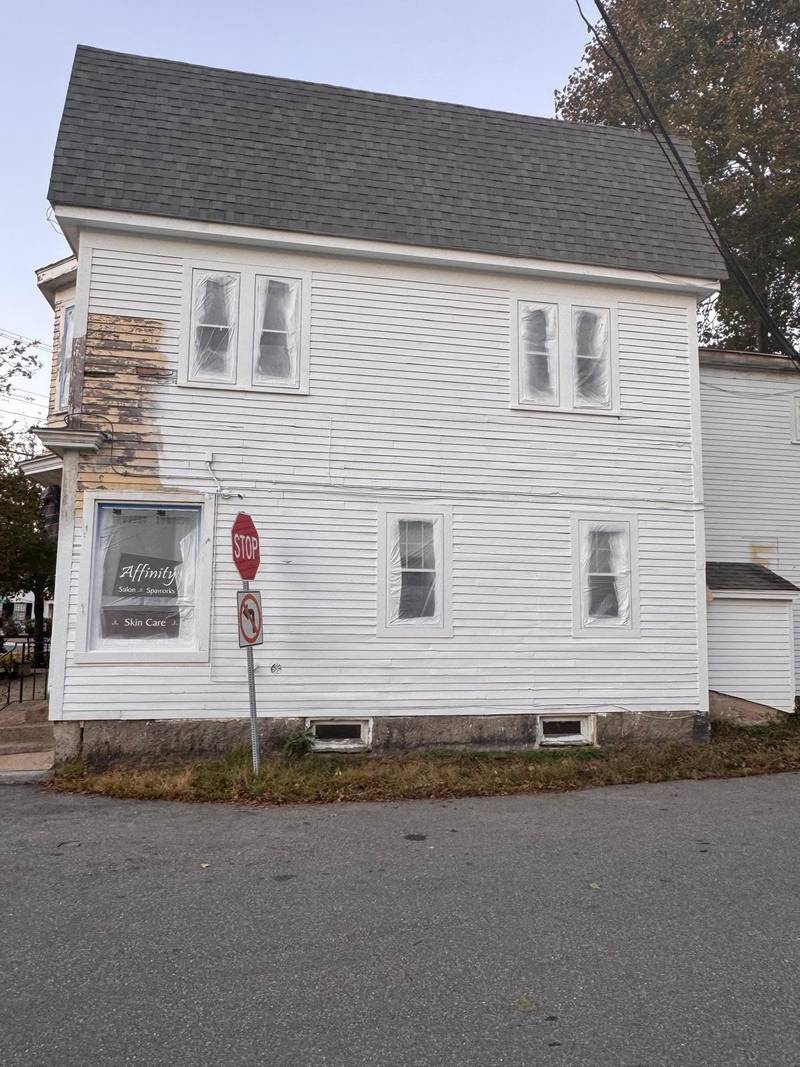 Corner of a white house with siding removed for repair.