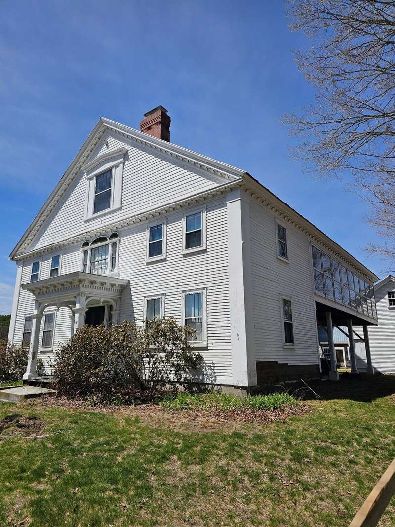 A white two-story house with white trim seen from the front lawn.